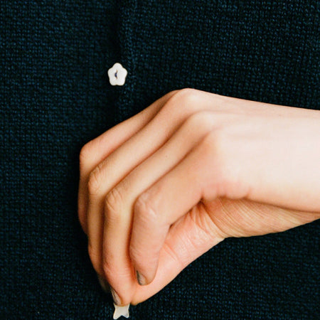 Close-up of the Francie Heirloom button doll’s cardigan in ink, showing a flower-shaped pearl button