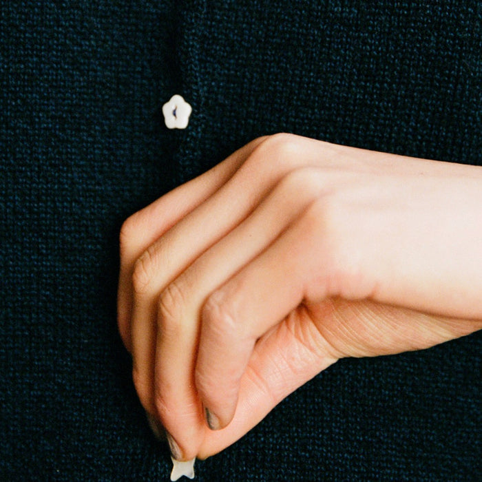 Close-up of the Francie Heirloom button doll’s cardigan in ink, showing a flower-shaped pearl button