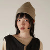 Francie Hinoki beanie in natural, a ribbed knit beanie worn with a cream jumper and black vest