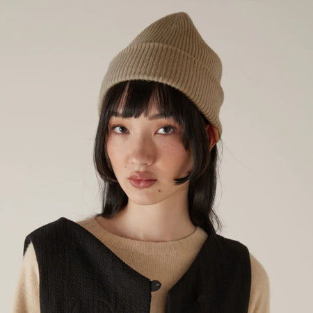 Francie Hinoki beanie in natural, a ribbed knit beanie worn with a cream jumper and black vest
