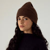 Francie Hinoki beanie in truffle brown, a ribbed knit beanie worn slouched with a black jumper