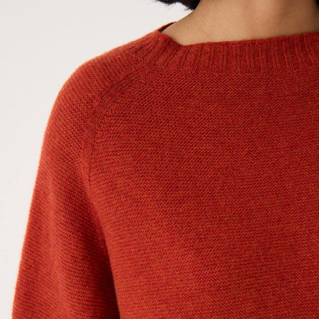 Close-up of the Francie Poet knit jumper in amber rust, showing the wide ribbed neckline and textured knit