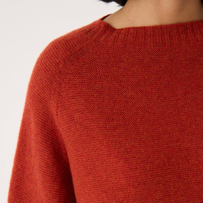 Close-up of the Francie Poet knit jumper in amber rust, showing the wide ribbed neckline and textured knit