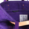 Inside the Immodest Cotton East West small canvas tote in purple, showing contrast stitching and inner label