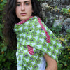 Woman wearing a Les Belles Vagabondes cotton scarf in green swirl print with red trim