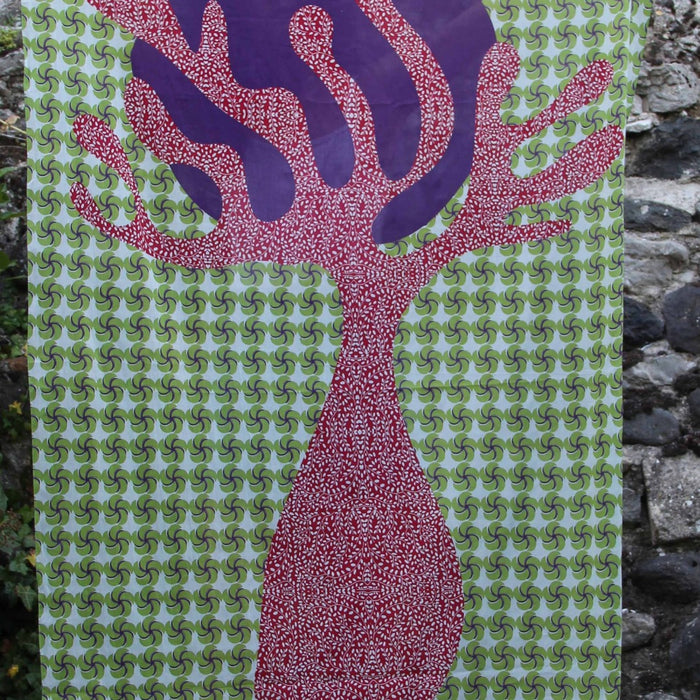 Les Belles Vagabondes cotton scarf with a pink tree print on green, hanging against stone
