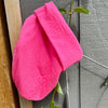 Manuelle Guibal Pepe fine knit beanie in fluoro pink, hung on a garden fence