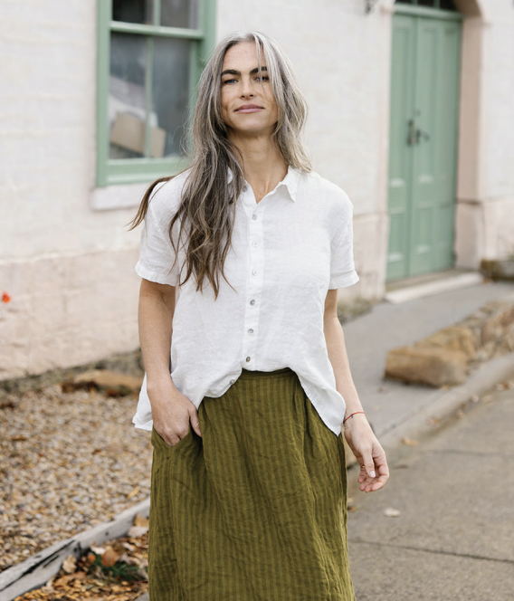 Metta Melbourne Cliff linen short sleeve shirt in white, worn with an olive skirt