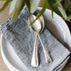 Metta Melbourne black houndstooth linen napkin set on a white plate with silver spoons