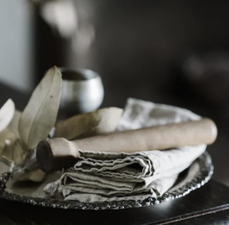 Metta Melbourne natural linen napkins stacked on a pewter plate