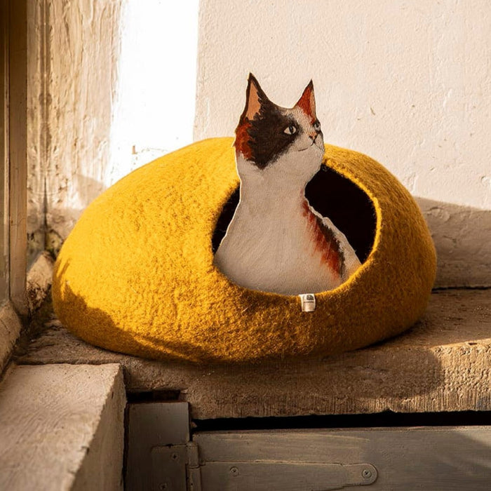 Muskhane felted wool cat basket in mustard yellow with a cat inside