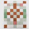 Nancybird geo patchwork kantha quilt in rust, green and white, hand-stitched cotton, laid flat