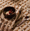 Nancybird geo flower tablecloth in brown and olive with a breakfast bowl