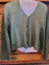 Green cardigan on a mannequin with a white shirt underneath against a wooden background