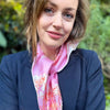 Woman wearing the Oliver Wilkinson Dancers pink silk scarf tied at the neck with a navy blazer