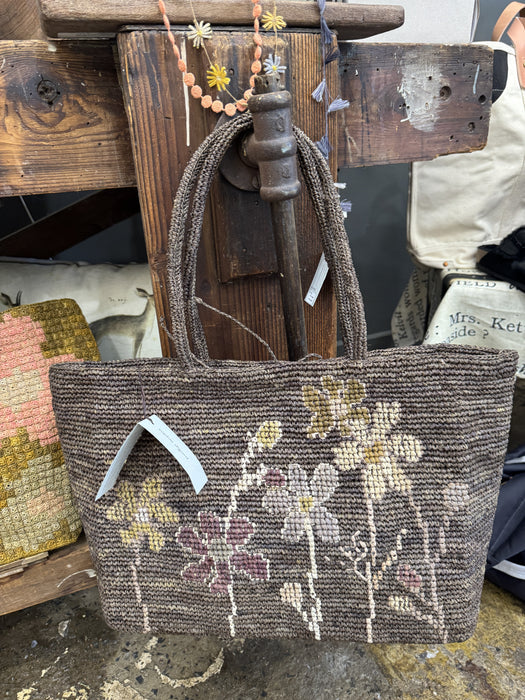 Sophie Digard brown floral crocheted raffia tote hanging in the Pomme shop