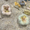 Close-up of the pastel wool flower appliques on the Sophie Digard raffia tote bag