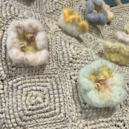Close-up of the pastel wool flower appliques on the Sophie Digard raffia tote bag