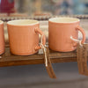 Three ceramic espresso cups with a hand-glazed finish, displayed on a wooden shelf with tags indicating they are designed by Anne Black and made in Denmark.