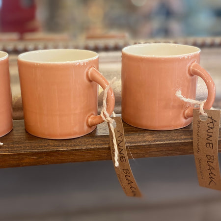 Three ceramic espresso cups with a hand-glazed finish, displayed on a wooden shelf with tags indicating they are designed by Anne Black and made in Denmark.