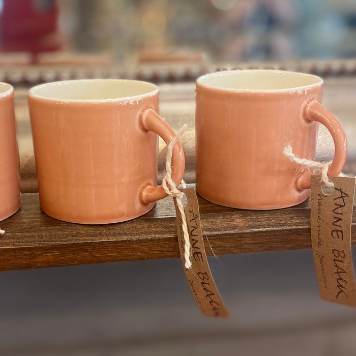 Three ceramic espresso cups with a hand-glazed finish, displayed on a wooden shelf with tags indicating they are designed by Anne Black and made in Denmark.