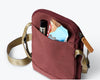 Bellroy City Pouch in plum, front pocket packed with sunglasses and a face mask