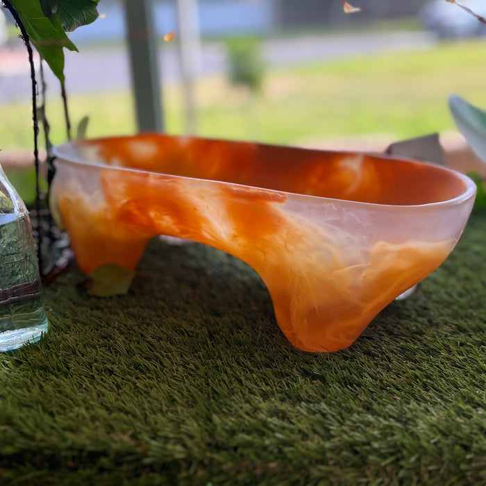 Dinosaur Designs Long offering bowl in orange swirled resin, outdoors on grass