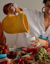 Dinosaur Designs large Rock jug in pollen yellow resin, pouring at a set table