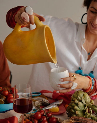 Dinosaur Designs large Rock jug in pollen yellow resin, pouring at a set table