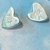 Flick Pope silver heart stud earrings, hand-stamped 'Flick', on a blue painted card